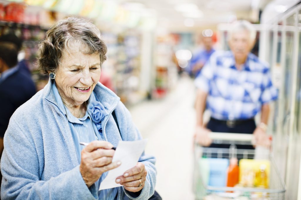 Smiling confident senior woman checks shopping list in supermarket