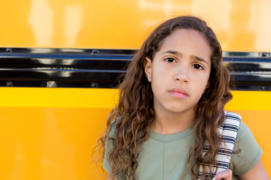 Young girl next to school bus