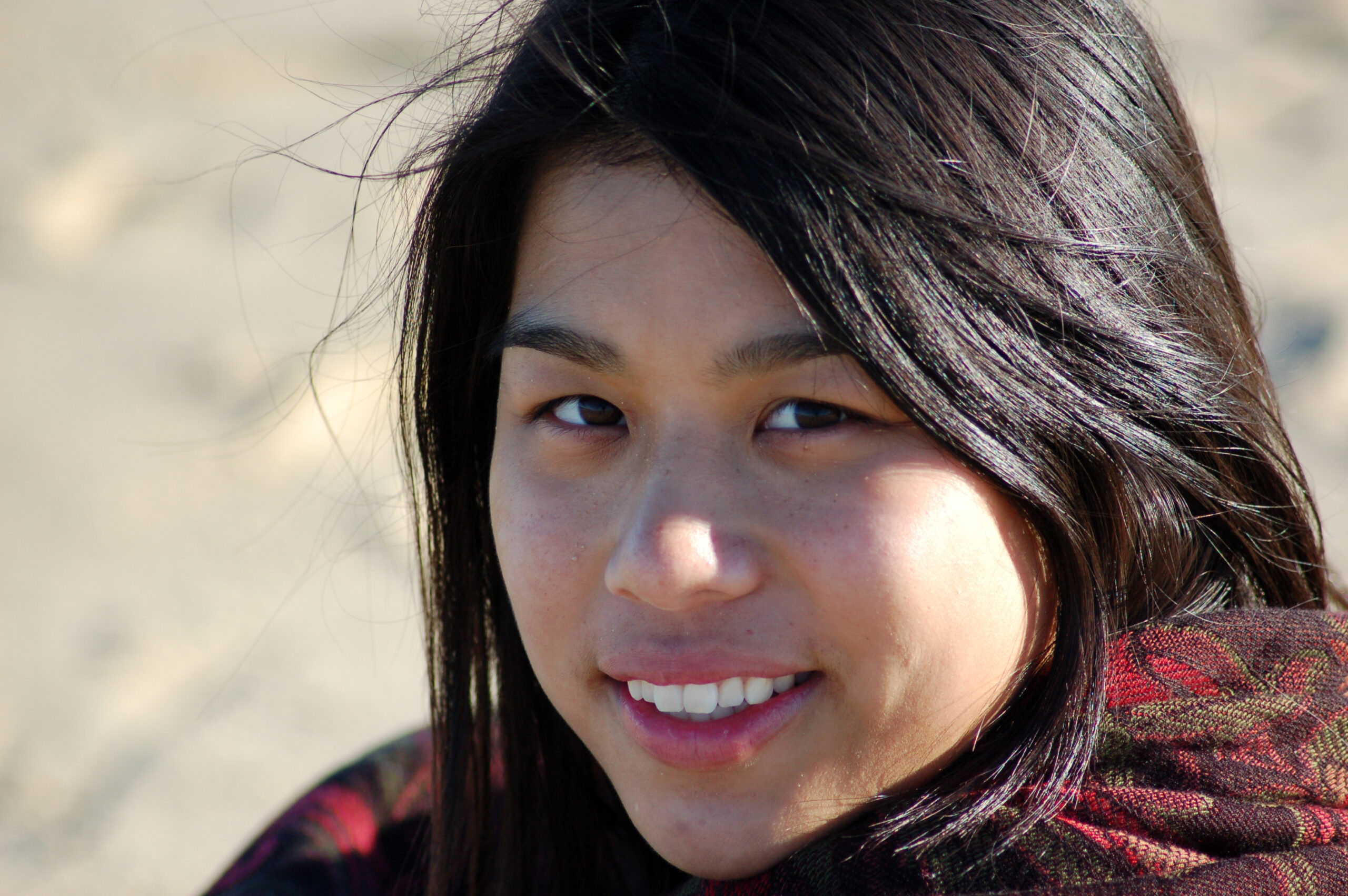 A native american woman smiles as a cold wind blows on the desert.