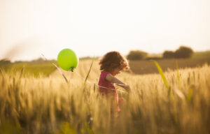 Cute little girl with balloons at field