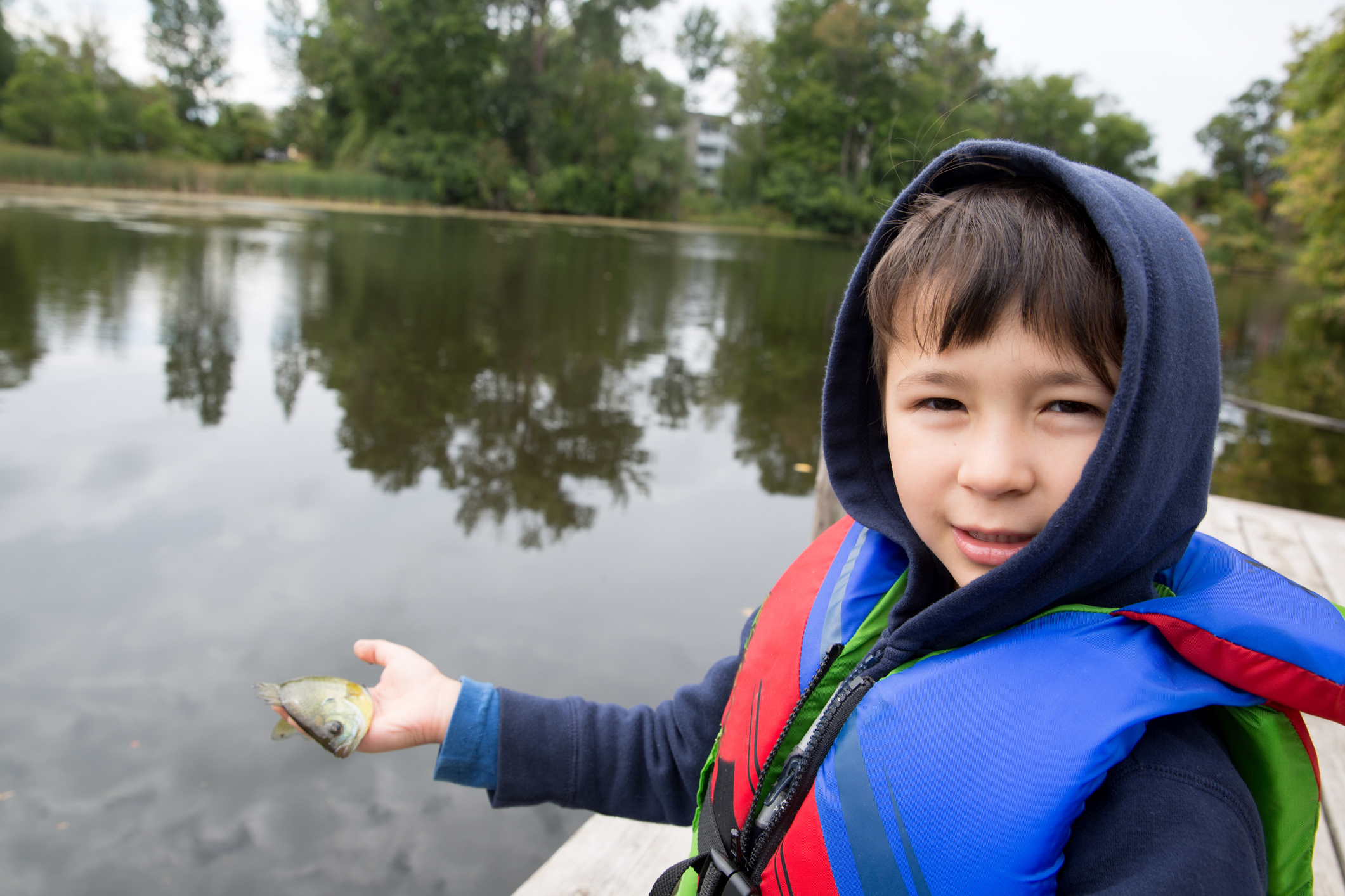 Little boy holds up his fish that he caught