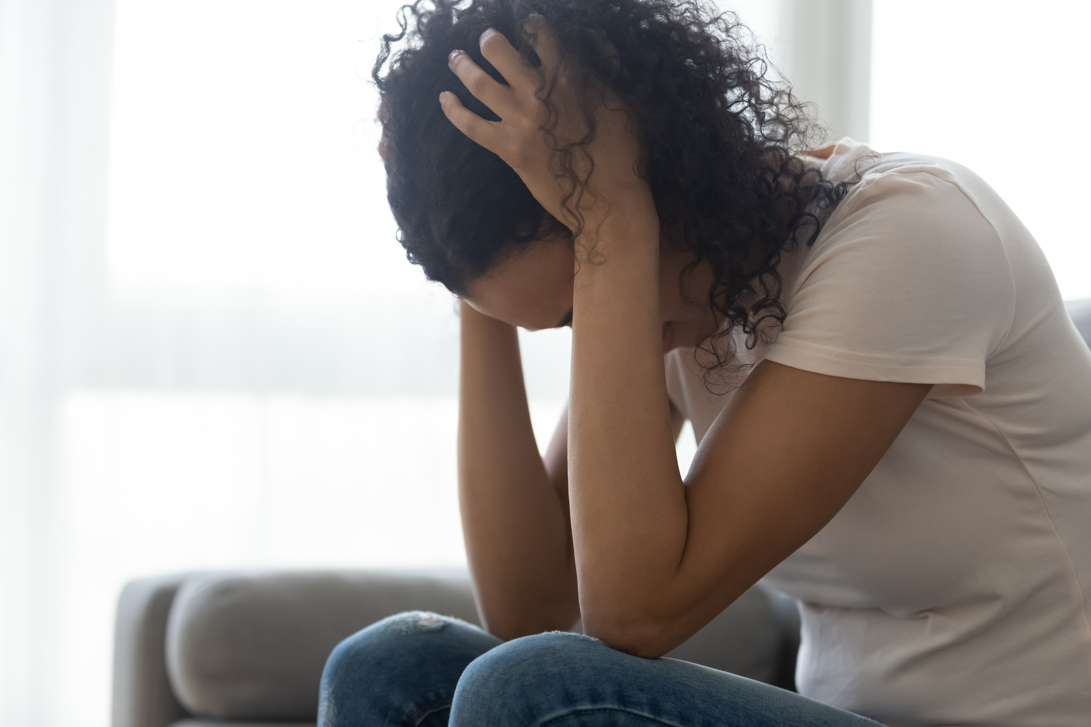 Sad hopeless black woman sit alone at home feeling depressed