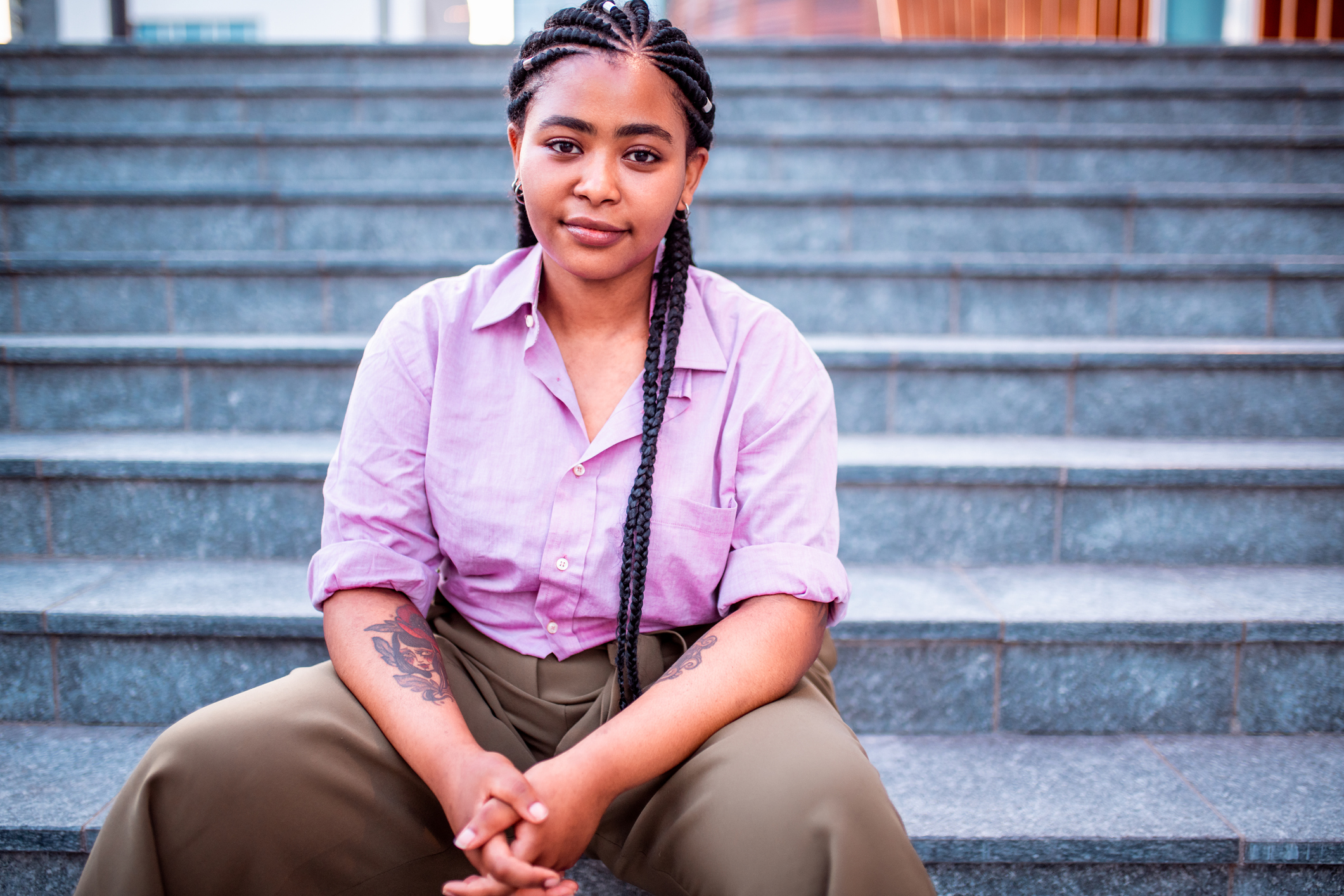 Teen: African-American smiling teen siting on outdoor stairs, hands clasped together.