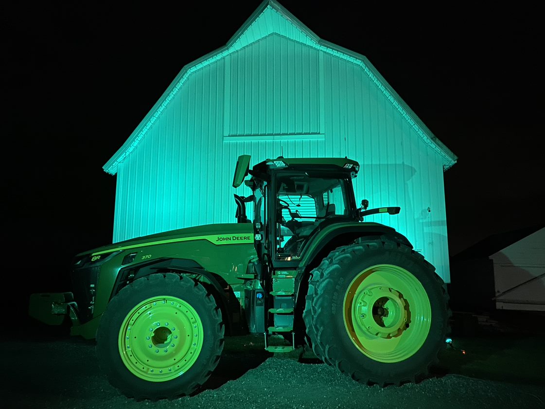 A green tractor in front of a barn (rural Mason City, Iowa) lighting up green for National Injury Prevention Day to raise awareness of the need to prevent injuries and violence in rural communities.