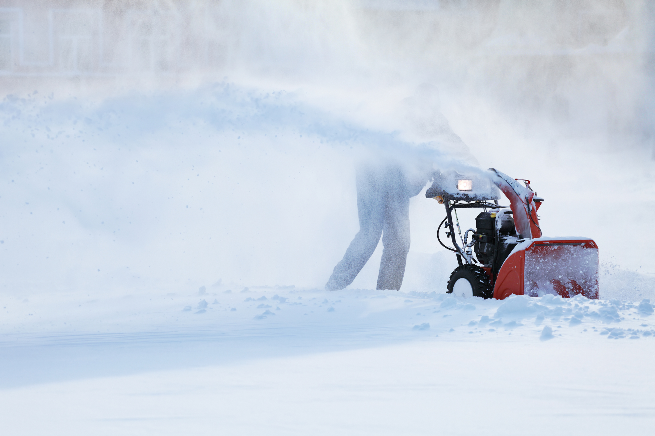 man with a snow blowing machine working in winter day