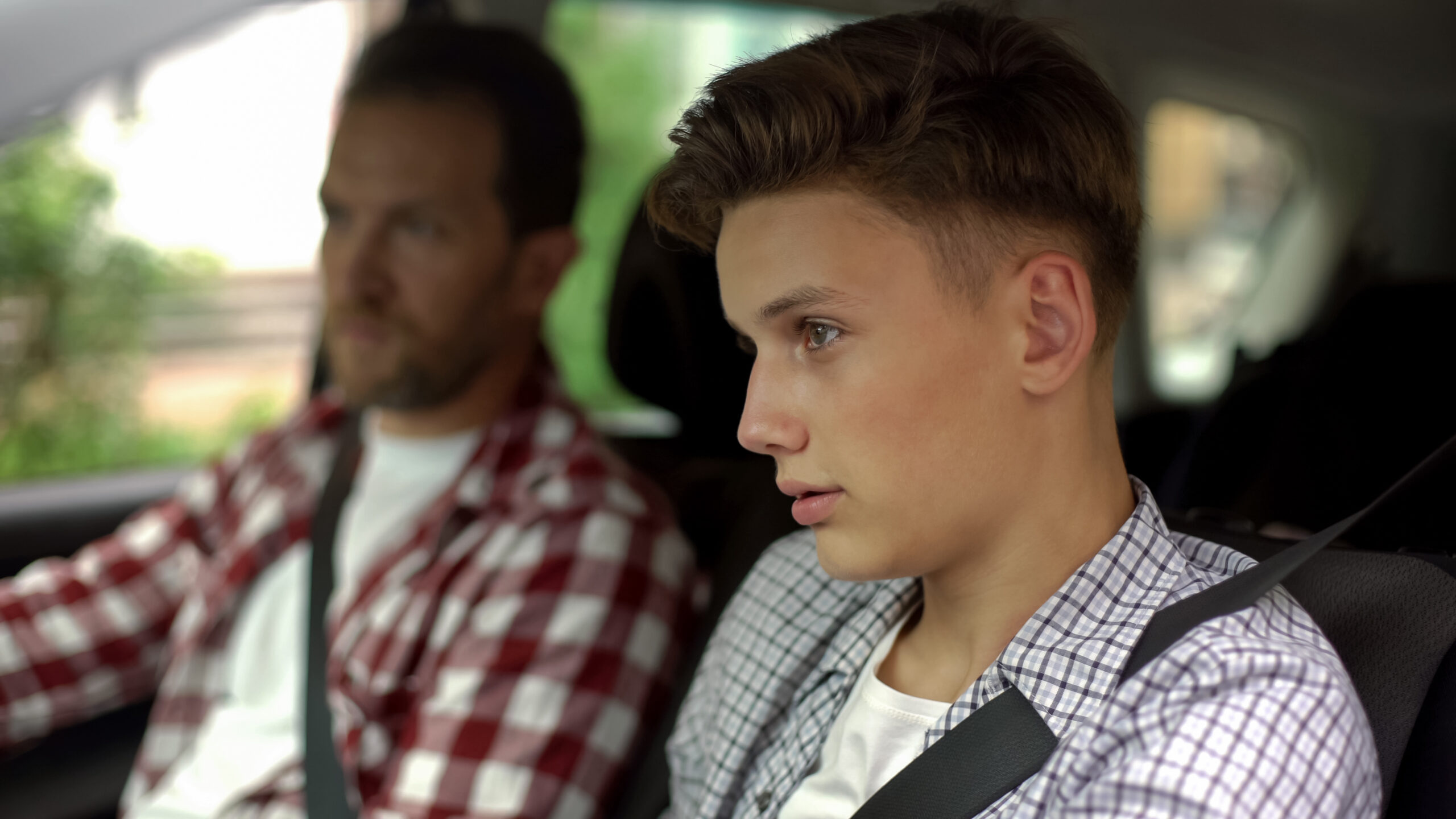 Male instructor teaching a male teen how to drive