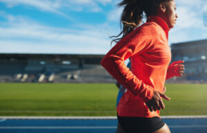 ide view of fit young woman running. African female athlete training on race track at athletics stadium.