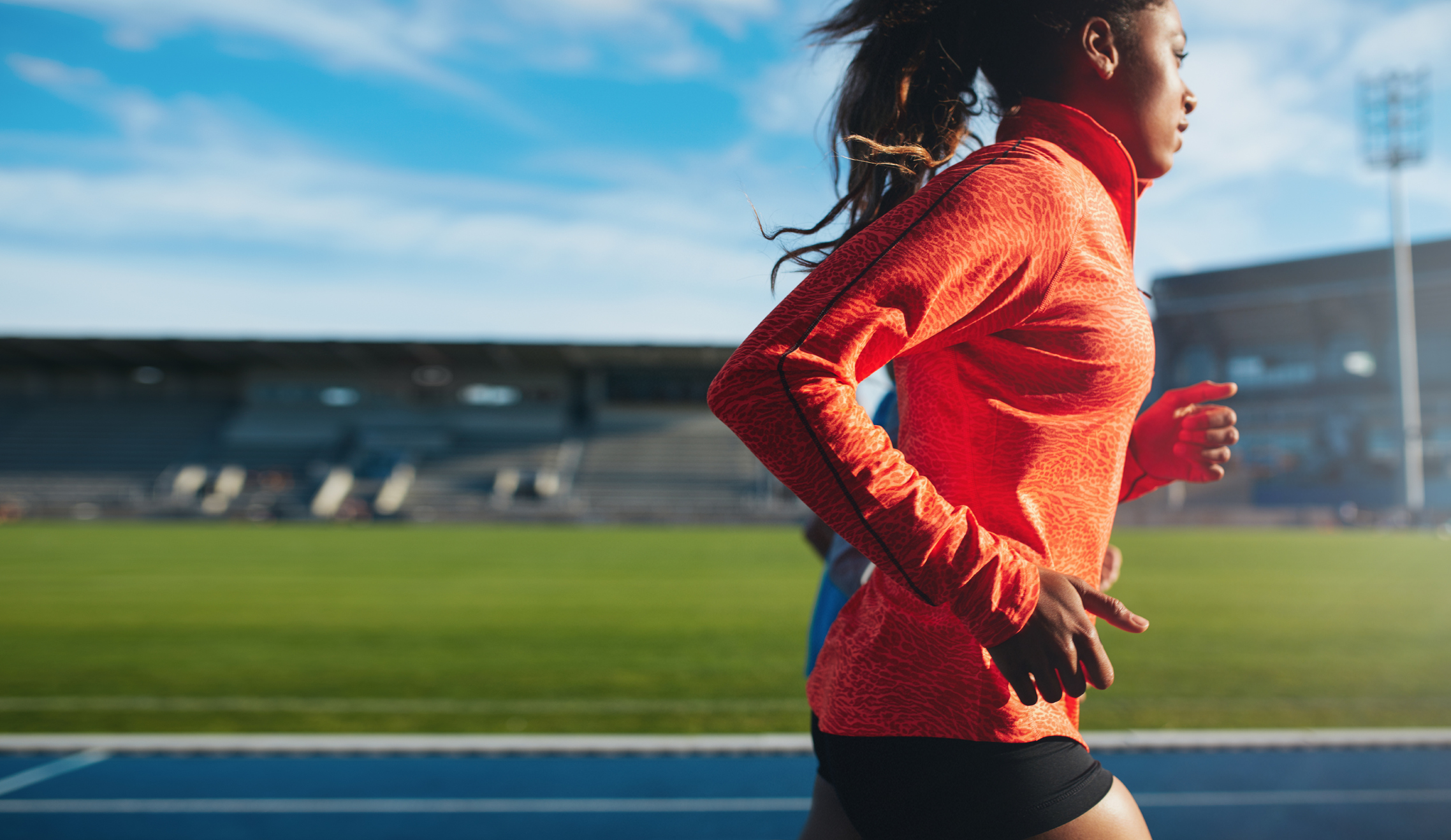 ide view of fit young woman running. African female athlete training on race track at athletics stadium.