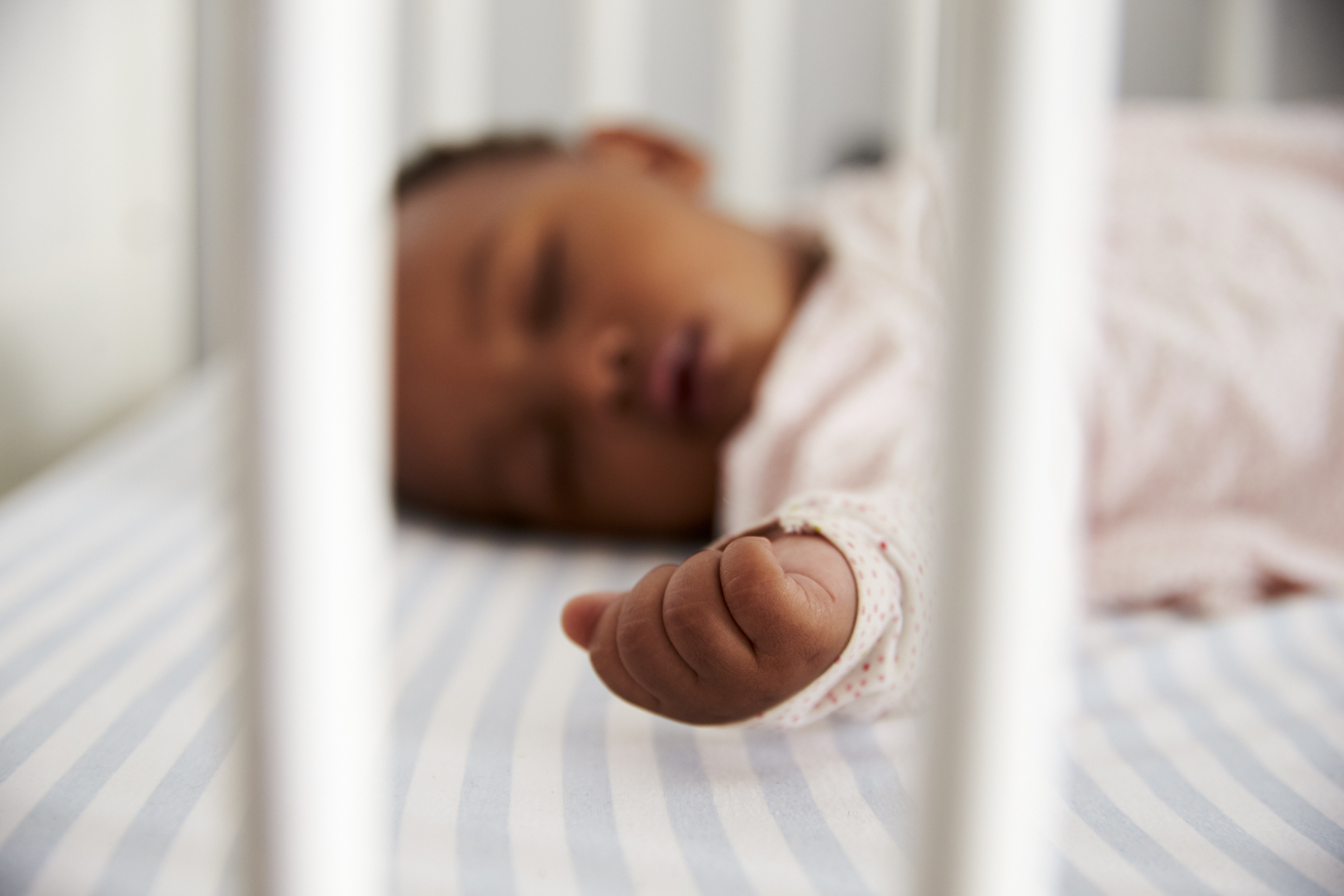 infant sleeping on her back in a crib
