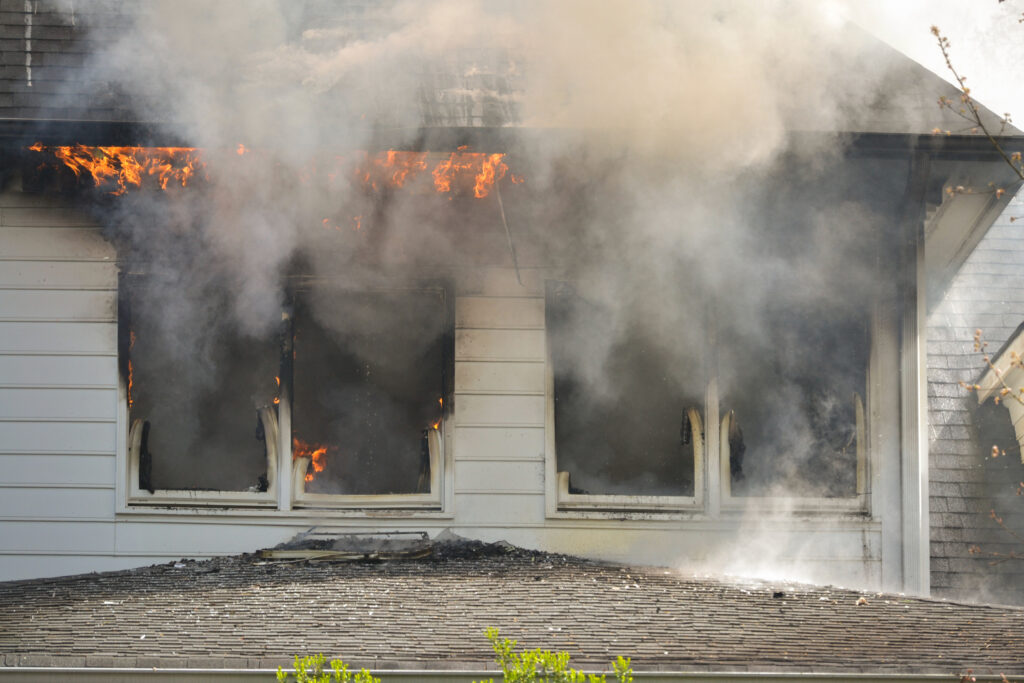 Fire and flames coming out of a two-story white house