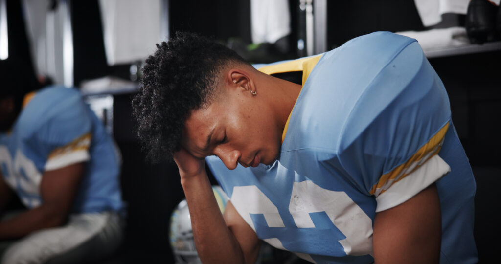 Young football player holds his head in pain